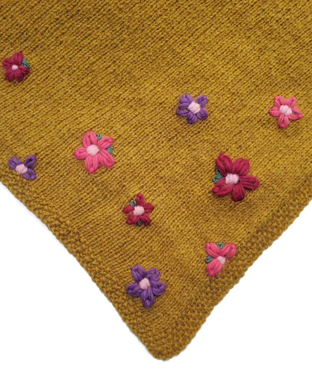 Aufsicht auf die bestickte Spitze eines senfgelben Dreieckstuchesckten Bluemn