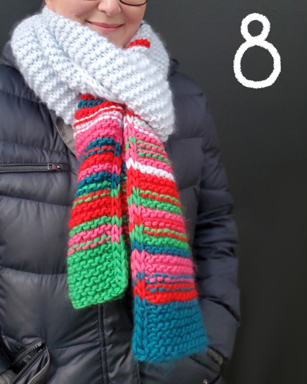 Modell trägt grobgestrickten Schal mit bunten Streifen an den Säumen