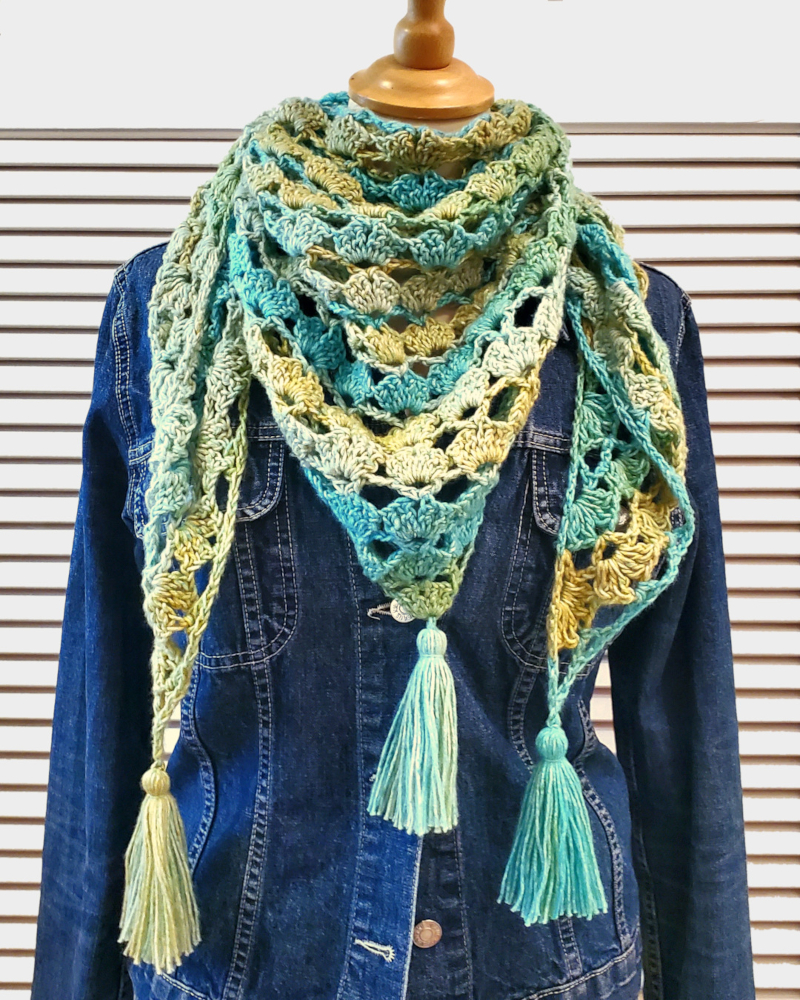 Gelb-grün-türkises Häkeltuch auf Schneiderpuppe, die eine Jeansjacke trägt