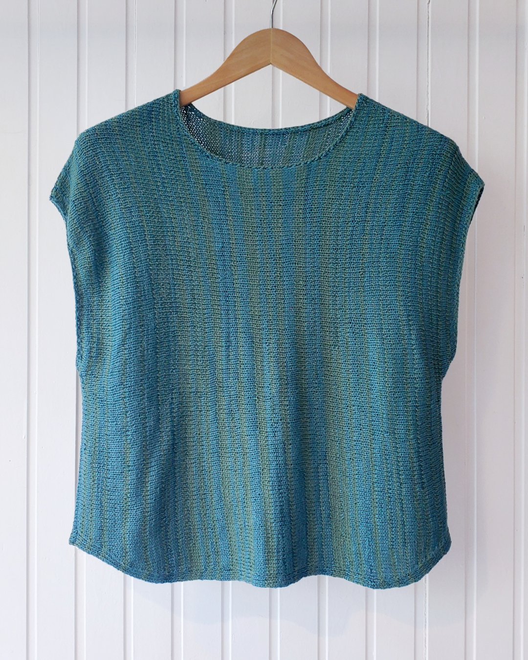 Petrol-grünes, ärmelloses Strickshirt auf Holzbügel