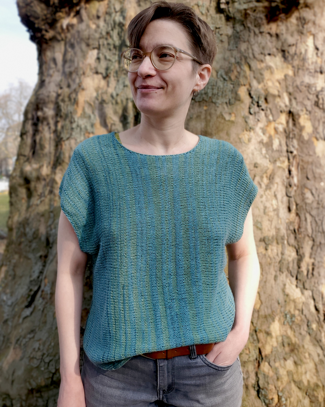 Modell trägt petrol-grünes, ärmelloses Strickshirt