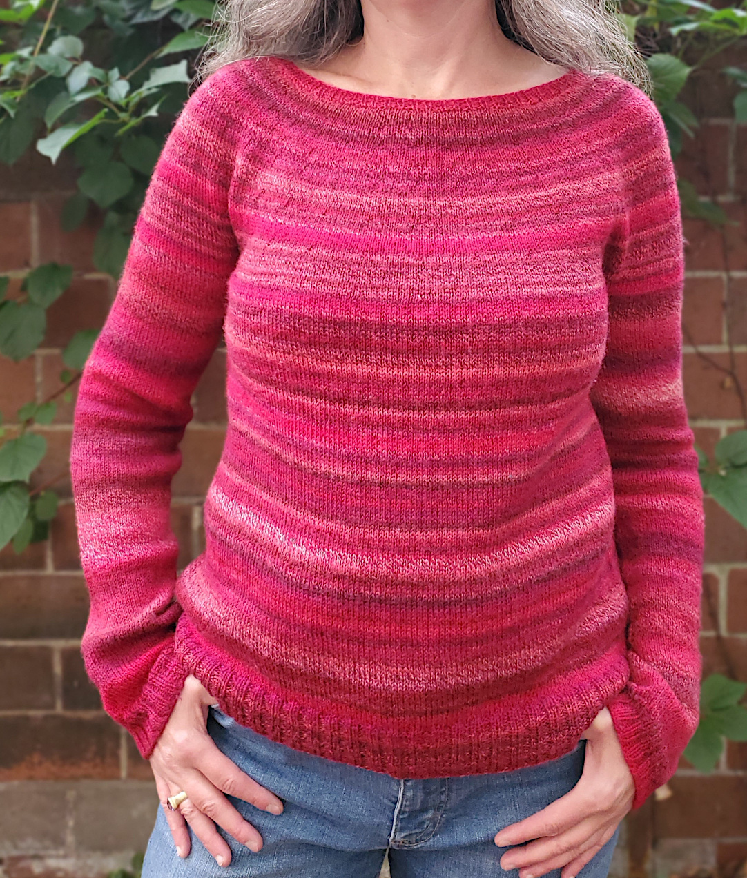 Modell trägt Rundpassenpullover aus rot-pinkem Multicolorgarn.